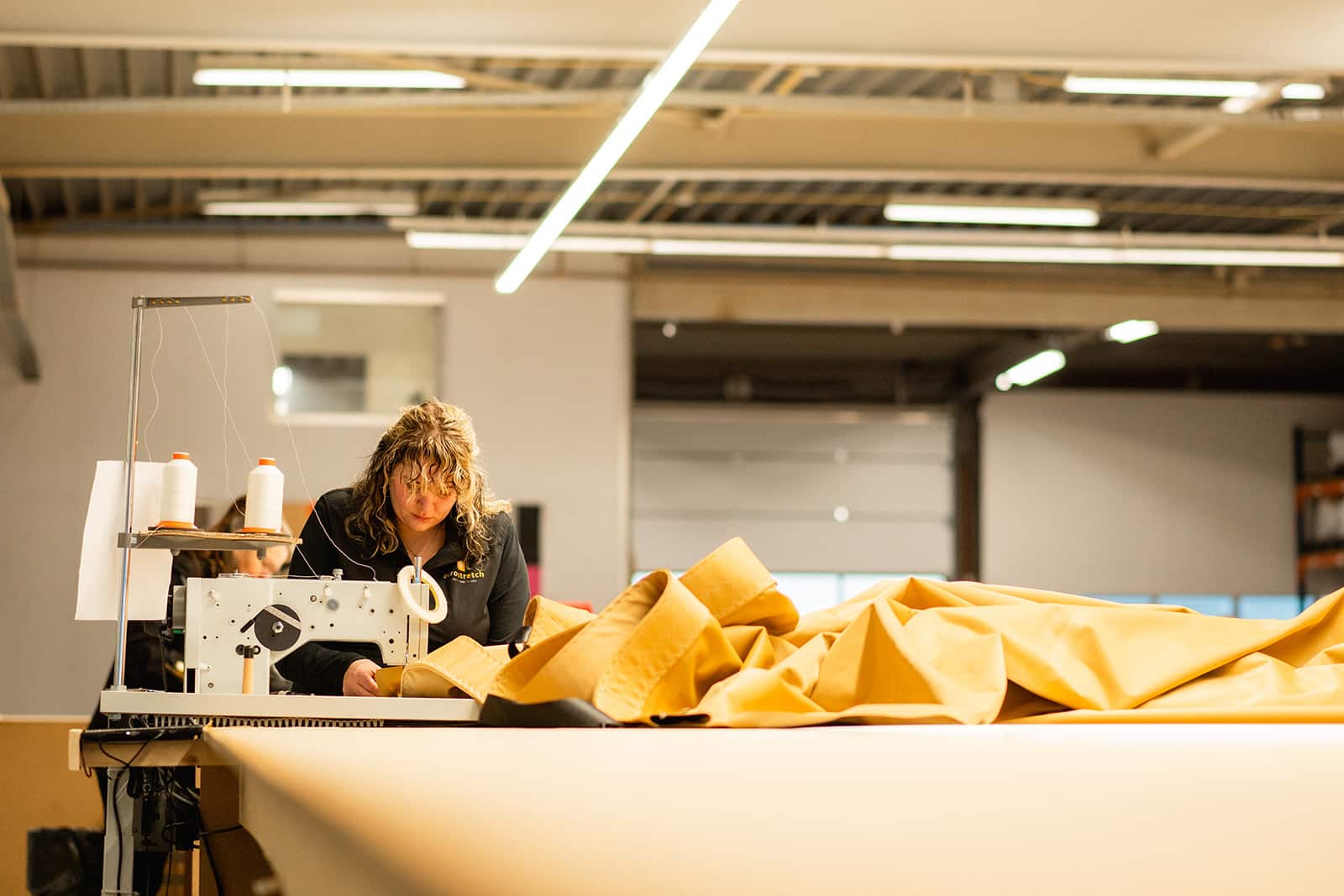 Confectiemedewerker aan confectietafel met een grote zandkleurige stretchtent