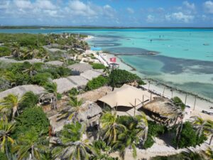 Dronefoto van kustlijn met stretchtent en turkoois water